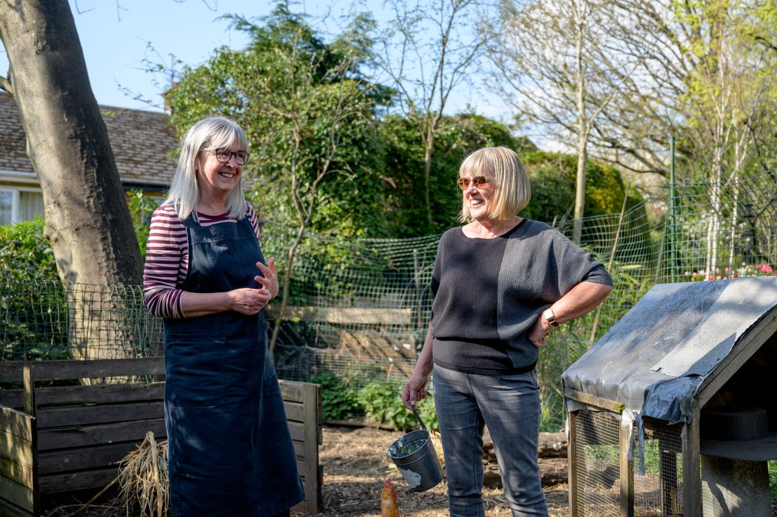 Two women talking and smiling in a garden.